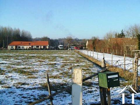Le chemin de campagne (chemin rural) donnant accès au terrain. on y aperçoit la maison du voisin le plus proche. 