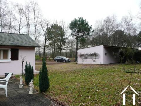 Vue de la terrasse qui est accessible à partir de la chambre à coucher principale. D'ici vous regardez à l'extérieur sur le jardin arrière, la région boisée et également le double garage de la propriété et l'abri de voiture.  