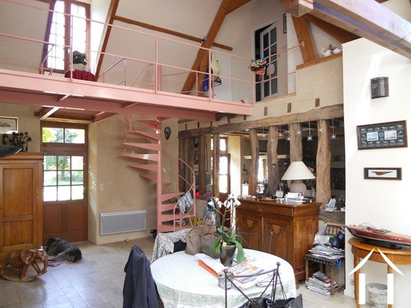 The vaulted part of the sejour which shows the kitchen (beyond the old oak upright beams); the modern gantry that spans the area to give access to the two bedrooms upstairs, and the dining area which is just at the beginning of the modern extension running at right angles to this impressive room.