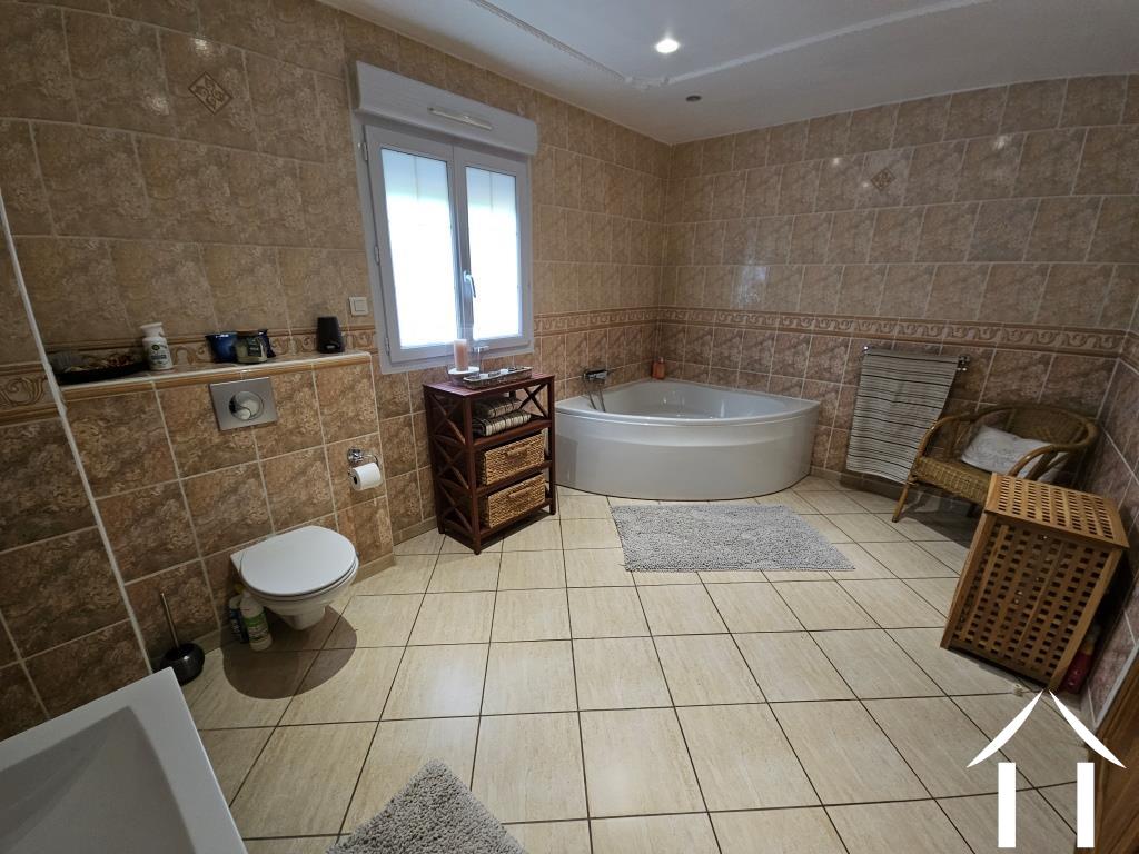 Salle de bain avec baignoire d'angle, douche, lavabo et toilettes